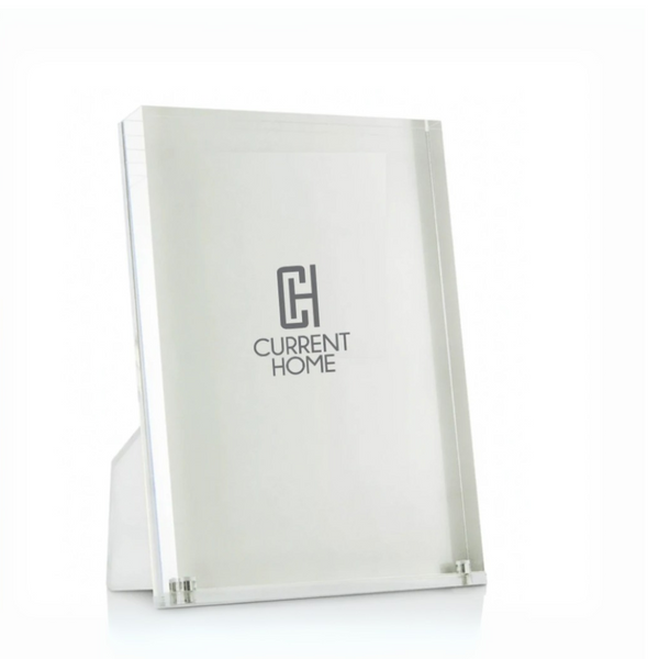 The Tizo Lucite Clear Frame is a simple, modern, and minimalist rectangular acrylic picture frame that stands upright on a white surface.