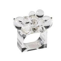 The Kim Seybert Cloud Napkin Ring Set of 4 features clear, rectangular Lucite rings adorned with varying sizes of transparent acrylic baubles, offering a modern, sculptural design.