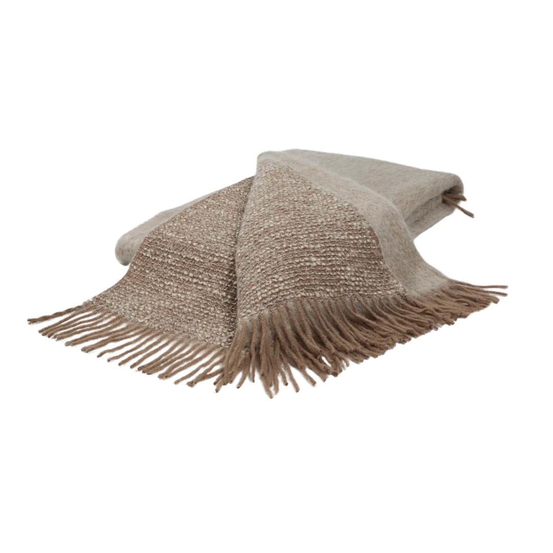 The Coco Throw by Mantas Ezcaray is a double-sided beige and light brown blanket with fringed edges, crafted in a Chanel-inspired style and shown on a white background.