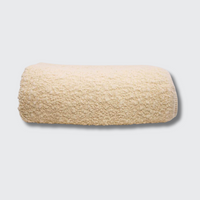 The Uniquity Kusama Boucle Cream Throw, featuring a textured cream weave, is neatly folded and displayed against a plain light gray background.