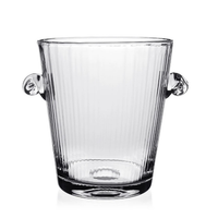 The William Yeoward Corinne Champagne Bucket is a clear, handmade crystal piece featuring vertical grooves and two round side handles, evoking Jazz Age elegance. It is photographed against a white background.