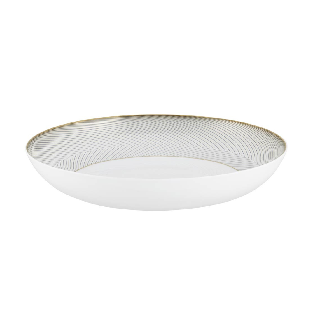 The Oskar Dinnerware bowl by Raynaud is round and white with a wide rim, accented by a thin gold geometric pattern. Its smooth, minimalist ceramic design is ideal for modern tablescapes.