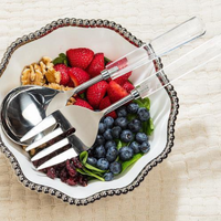 A bowl of fresh spinach with strawberries, blueberries, walnuts, and dried cranberries is served with the Abbott Collection Crystal Handle Salad Server Set resting on the edge, all placed on a textured cream cloth.