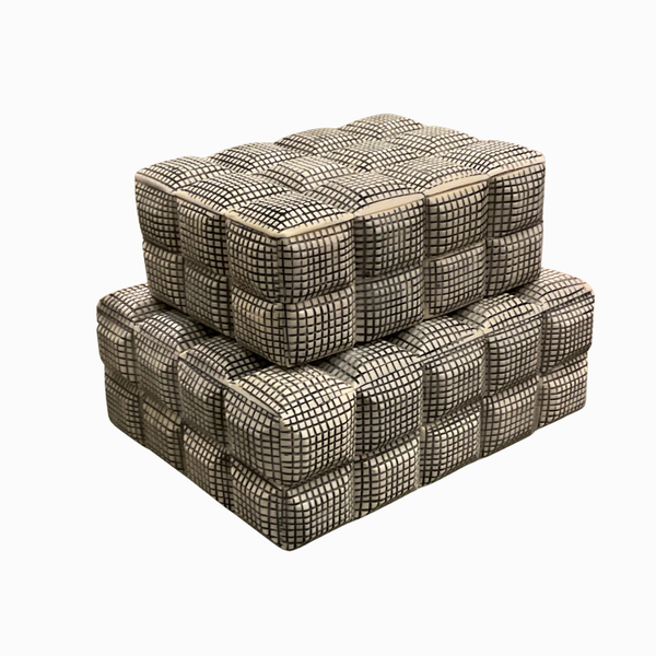 Two Cubie Box ottomans by A Sanoma Inc, featuring a bone-checkered box pattern in small black and white squares, are stacked against a white background—perfect as edgy decorative accents for modern homes.