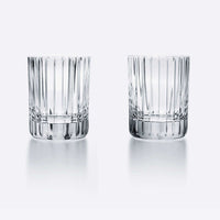 Two clear Baccarat Harmonie Barware glasses by Baccarat, featuring an elegant faceted design, are placed side by side on a white background with subtle reflections beneath them.