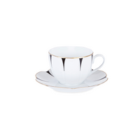 The Drops Dinnerware by Molecot features a white porcelain teacup and saucer with black abstract patterns and a gold edge, paired with a flower-shaped plate, all displayed on a white background.