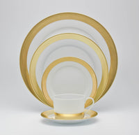 The Royal Limoges Danielle Gold Dinnerware set, featuring gold-banded porcelain pieces—dinner plate, salad plate, bread plate, soup bowl, cup, and saucer—is arranged in a neat overlapping display on a plain white background.