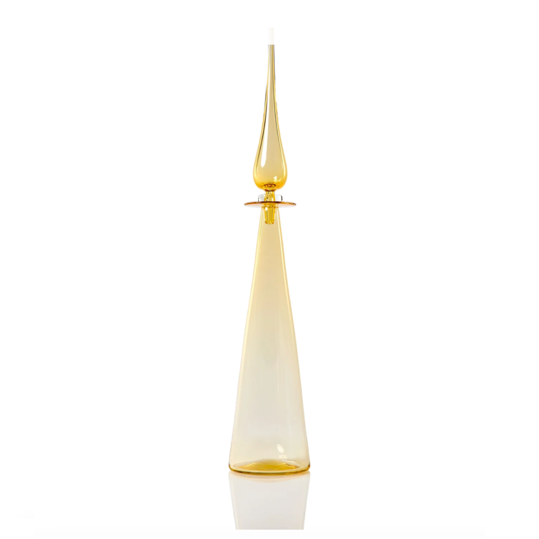 The Cariati Petite Decanter Straight Cone features a tall, elegant, handblown translucent yellow glass with a narrow neck, teardrop stopper, and flared base—modern barware sophistication set against a white background.