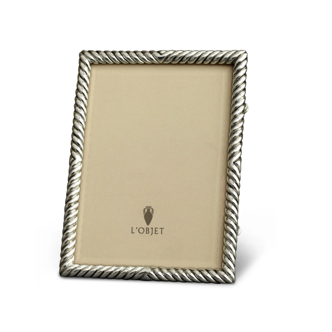 The L'Objet Deco Twist Platinum Frame is a handcrafted rectangular silver picture frame, featuring a twisted rope design, a beige logo insert at the center, and stands upright at a slight angle.