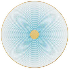 Raynaud’s Aura Dinnerware features a central gold irregular hexagon with thin blue concentric lines radiating outward on a white background, finished with a gold scalloped rim for a modern, elegant touch.