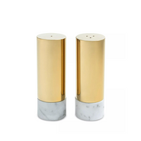 The Anna New York Dual Salt & Pepper Shakers Marble & Gold Set of 2 features two cylindrical shakers with Italian Carrara marble bases and gold metal tops, displayed side by side for a modern luxe touch.