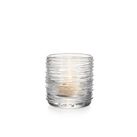 The Simon Pearce Echo Lake Tealight in Gift Box is a small, clear glass holder with horizontal textured lines, elegantly cradling a lit candle against a white background.