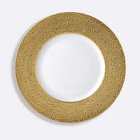 The Ecume Dinnerware Gold by Bernardaud is a white ceramic plate featuring a wide, textured gold rim with raised dot patterns, capturing the elegance of Limoges porcelain. Photographed on a plain light background.