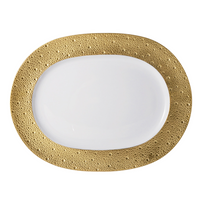 The Bernardaud Ecume Dinnerware Gold plate features an oval shape, a white surface, and a wide, textured gold rim with raised dots for a touch of contemporary elegance.