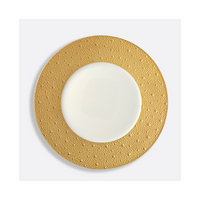 The Bernardaud Ecume Dinnerware Gold plate features a round white design with a wide, textured gold rim adorned with dots, shown on a plain white background—a striking piece of contemporary tableware.