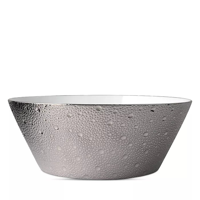 The Ecume Platinum Dinnerware by Bernardaud features a wide, round bowl with a white interior and textured metallic silver exterior with raised dots, offering a modern, elegant look for contemporary table settings.