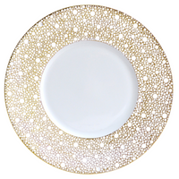 The Bernardaud Ecume Dinnerware Mordore is a round white porcelain plate with a wide rim accented by an intricate gold dotted pattern, while its center remains beautifully plain for a luxurious, elegant look.