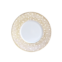 The Bernardaud Ecume Dinnerware Mordore plate is round white porcelain, showcasing a wide rim with an intricate gold dotted pattern and a plain white center, photographed on a white background.