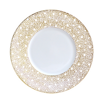 The Bernardaud Ecume Dinnerware Mordore is a white porcelain plate with a wide rim adorned by an intricate gold dot pattern, giving this piece an elegant and decorative look.
