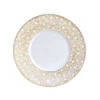 The Bernardaud Ecume Dinnerware Mordore is a white porcelain plate with a wide rim embellished by an intricate gold dotted circular pattern, while its center remains plain, highlighting the elegant design against the white background.