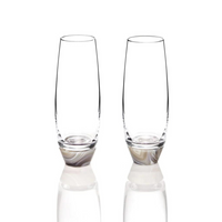 The Elevo Champagne Smoke Agate Glasses Set of 2 by Anna New York features two empty, clear lead-free crystal tumblers with thick bases, standing side by side on a reflective white surface against a plain white background.