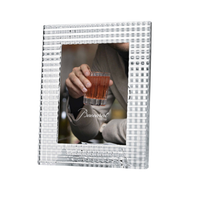 The Baccarat Eye Photo Frame, crafted from clear textured crystal, displays a photo showing only the lower face and hand of a person in a beige sweater holding a glass of red drink, with "Baccarat" written on the image.