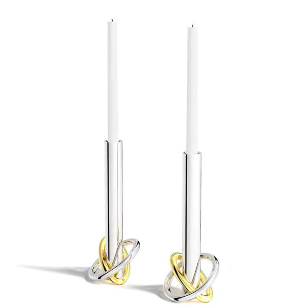 The Anna New York Ring Candle Holder Set of 2 features stainless steel holders with intertwined gold and silver bases, topped with white taper candles—an elegant accent for any modern decor.