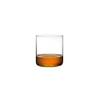 A Finesse Barware Set of 4 by Nude Glassware features clear lead-free crystal tumblers, shown here with a splash of amber liquid, possibly whiskey, against a white background.