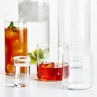 Four clear Finesse Barware glasses by Nude Glassware display assorted drinks: iced tea with mint, a tall drink with lime and ice, a short drink with ice and lime, and a shot with a salt rim. All are crafted from lead-free crystal.