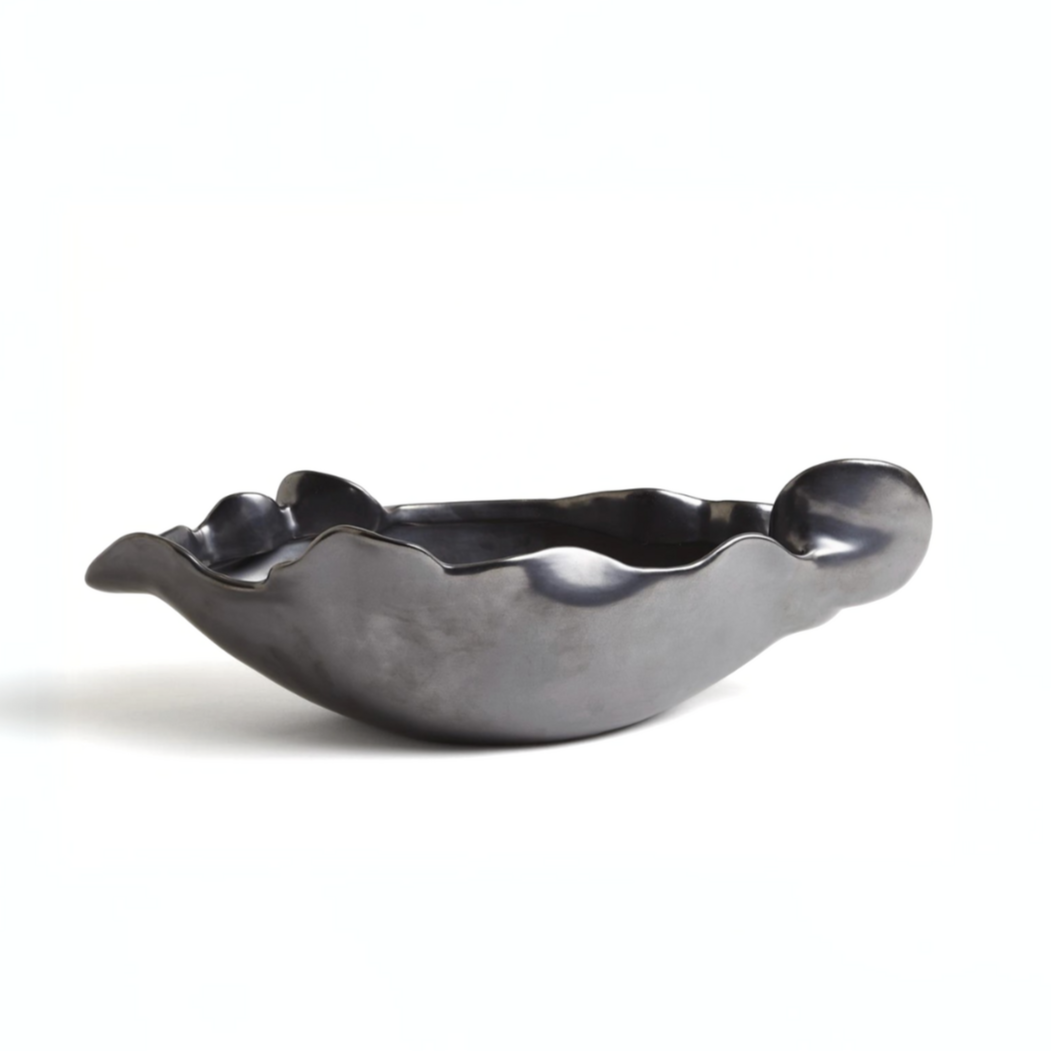 The Free Form Graphite Bowl by Global Views/Surya is a black ceramic piece from Portugal, featuring a matte graphite finish, wavy uneven edges, and an abstract shape, displayed on a plain white background.