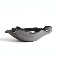 The Free Form Graphite Bowl by Global Views/Surya is a black ceramic piece from Portugal, featuring a matte graphite finish, wavy uneven edges, and an abstract shape, displayed on a plain white background.