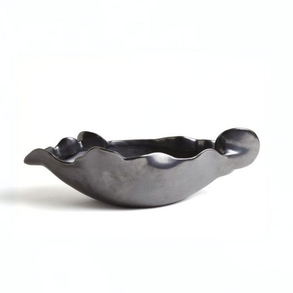 The Free Form Graphite Bowl by Global Views/Surya is a black ceramic piece from Portugal, featuring a matte graphite finish, wavy uneven edges, and an abstract shape, displayed on a plain white background.