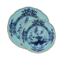 Two Ginori 1735 Oriente Italiano Dinnerware Iris plates with scalloped edges, gold trim, and intricate dark blue floral chinoiserie motifs overlap on a white background.