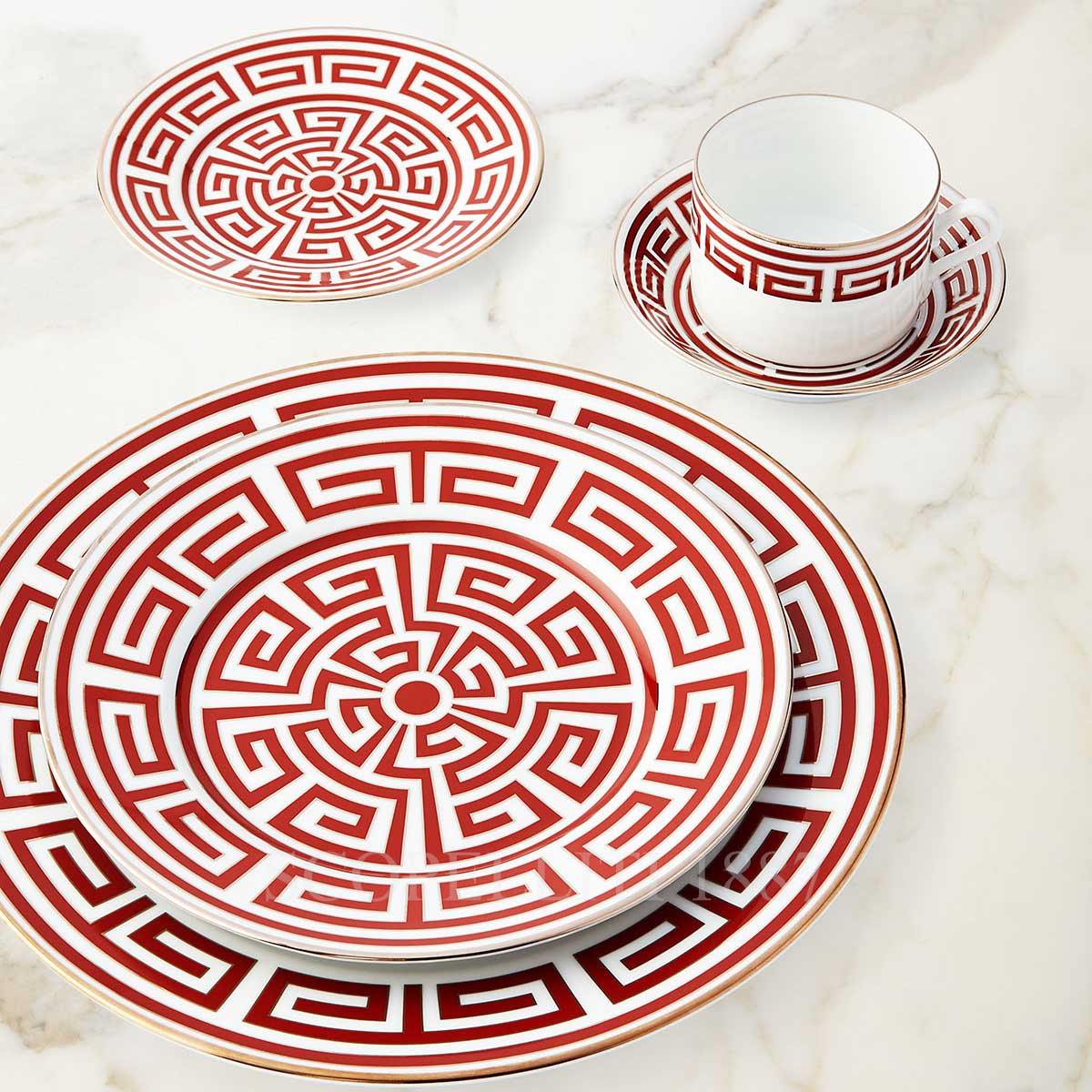 Labirinto Dinnerware Scarlatto by Ginori 1735, featuring red and white porcelain plates, cup, and saucer with geometric motifs, is arranged on a marble surface. Made in Italy.