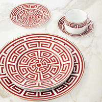 Labirinto Dinnerware Scarlatto by Ginori 1735, featuring red and white porcelain plates, cup, and saucer with geometric motifs, is arranged on a marble surface. Made in Italy.