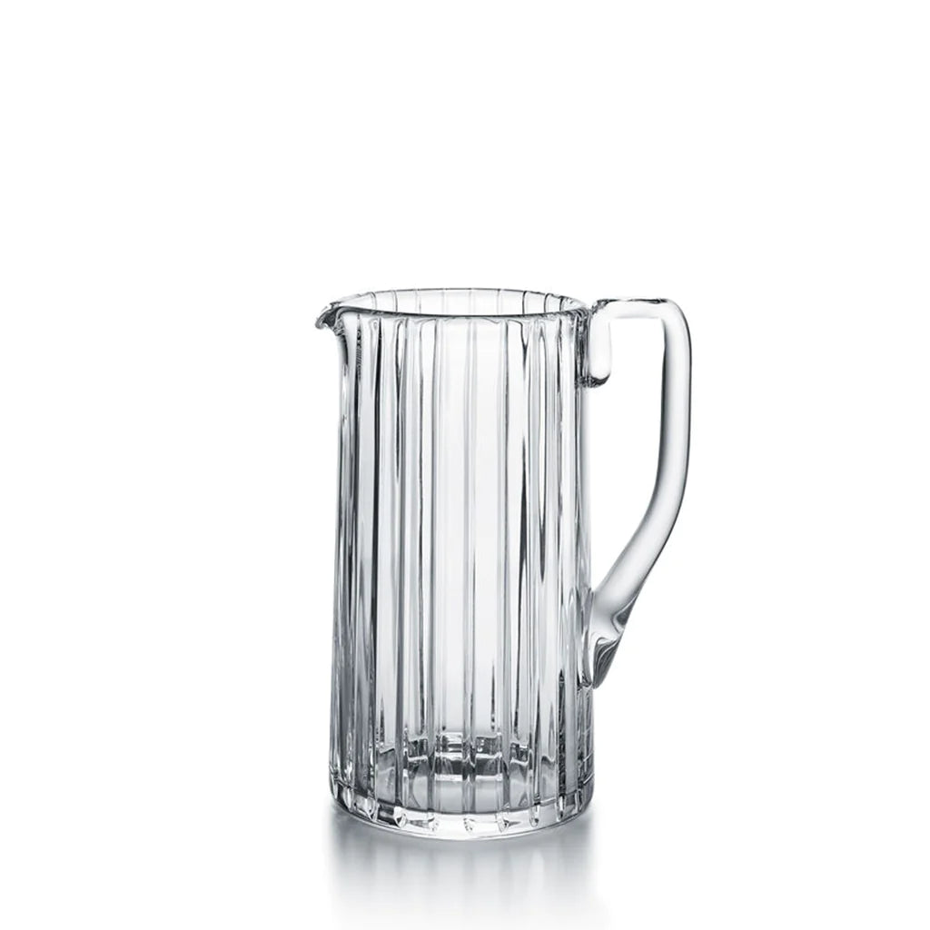 The Baccarat Harmonie Pitcher features vertical grooves, a handle, and a pouring spout, displayed against a plain white background.
