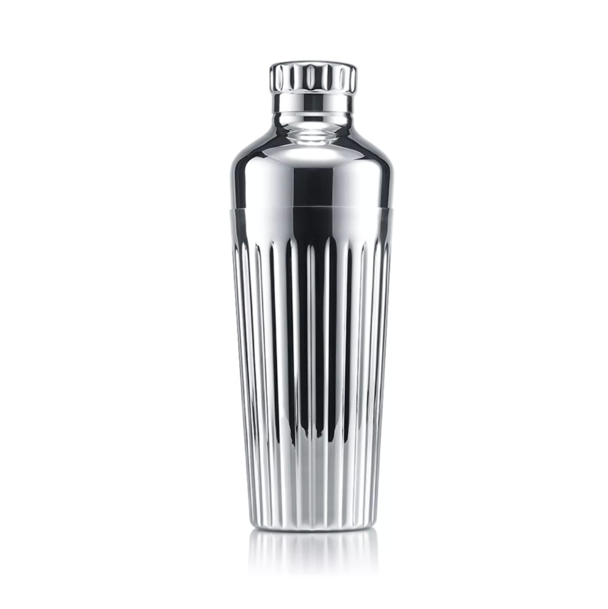 A gleaming Baccarat Harmonie Shaker with vertical grooves stands upright against a white background, highlighting its elegant stainless steel design.