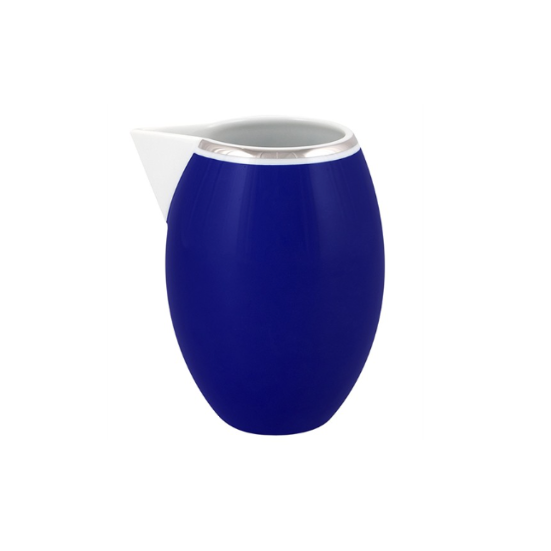 The Vista Alegre Harvard Dinnerware pitcher features a modern oval shape with a glossy blue body, white spout, and silver rim—styled in classic New England design—perfect for porcelain settings, shown on a plain white background.