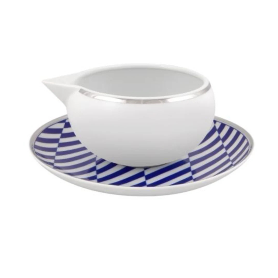 The Vista Alegre Harvard Dinnerware creamer sits on a saucer with a blue and white geometric pattern, bringing classic New England style to your collection.