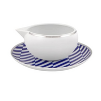 The Vista Alegre Harvard Dinnerware creamer sits on a saucer with a blue and white geometric pattern, bringing classic New England style to your collection.