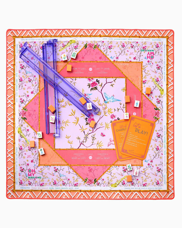 The Oh My Mahjong Mahjong Mats feature a floral, geometric-patterned non-slip surface with purple racks, orange cards, and small tiles spread across a pink and orange neoprene mat.