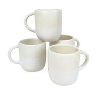 Four white Urban Dinnerware ceramic mugs by Alex Marshall Studios, featuring rounded shapes and handles, are stacked in pairs. Their smooth finish complements handmade stoneware plates. These mugs are microwave and dishwasher safe.