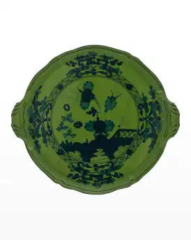 The Oriente Italiano Dinnerware Malachite by Ginori 1735 is a green porcelain plate with two small handles, adorned with dark blue floral and landscape motifs in the center and around the rim—a refined Italian tableware piece.