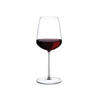 The Nude Glassware Stem Zero Powerful Red Wine Glass, filled halfway with rich red wine and set against a plain white background, showcases the elegance of full-bodied reds.