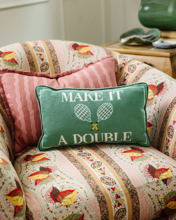 The Furbish Needlepoint Pillow - Make It A Double features green fabric, white text, and tennis rackets, making it a charming gift for tennis lovers who appreciate unique decor.