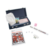 The Mini Travel Mahjong Set by Brouk & Co is beginner-friendly and includes a navy case, tiles, dice, scoring sticks, white pouch, racks, pink tile holder, and a guide—perfect as a portable set for play anywhere.