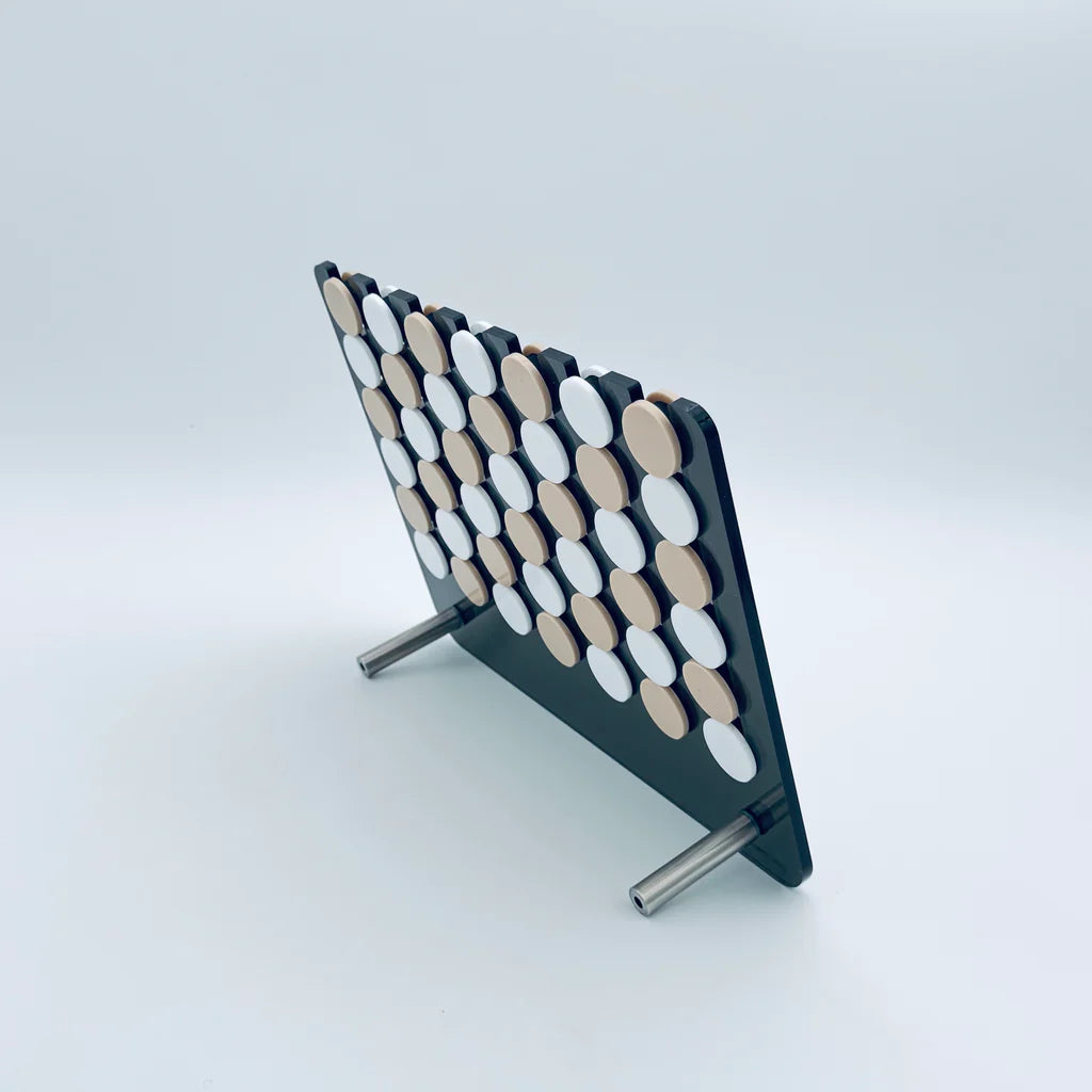 A standing Luxe Dominoes Connect Four El Cuatro board with alternating black and white discs, displayed against a plain white background. The classic four in a row game is supported by two metal legs.
