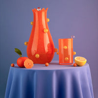 The Yakush Pollen Bloom Vase - Orange and matching glass with yellow knobs rest on a blue cloth with a tangerine, lemon half, and orange balls, set against a purple background.