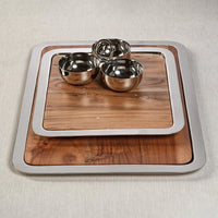 Three stainless steel bowls rest on two stacked Braxton Wood Serving Trays by Zodax, each featuring sleek metal edges. This elegant 2-in-1 set is perfect for use as a serving or charcuterie board, beautifully arranged on a light textured surface.