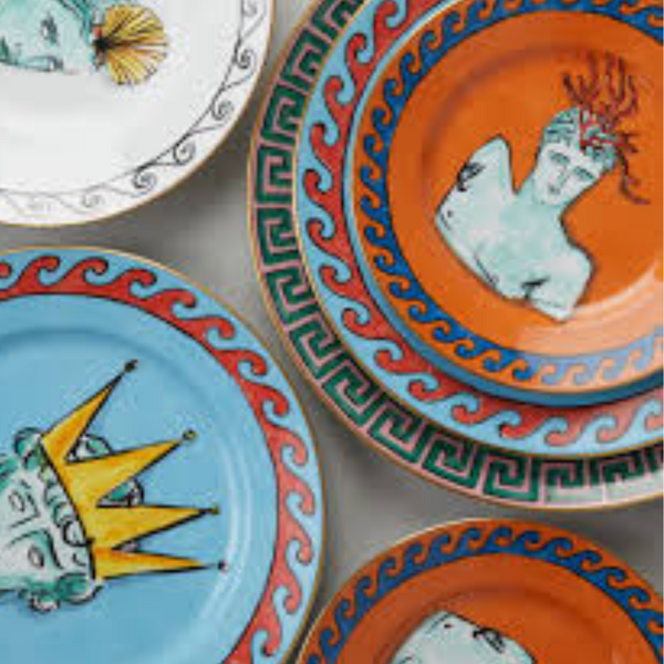 The Il Viaggio Di Nettuno Dessert Plate - Rock Orange by Ginori 1735 features vibrant orange borders and artistic face motifs, making it a striking piece of luxury tableware.